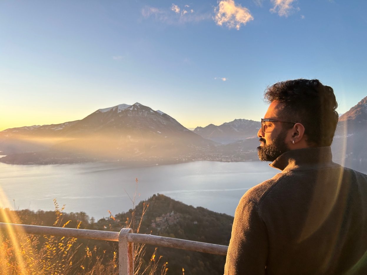 Arjun Ajith looking out over mountains and a lake at sunset