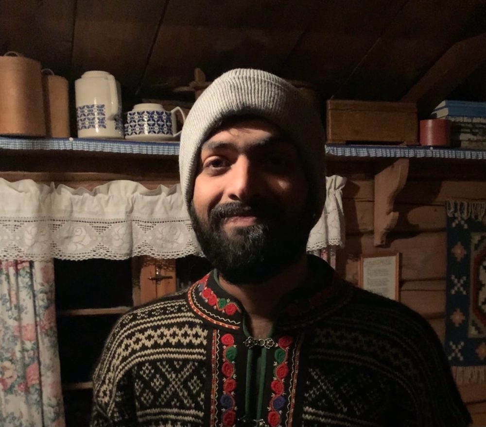 Arjun Ajith in a traditional Norwegian sweater at a mountain cabin